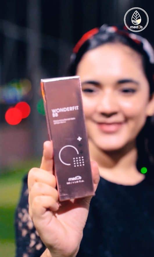 Woman presenting the MEDB Wonderfit BB Cream box, highlighting genuine Korean cosmetics and skincare available at MedB Bangladesh.